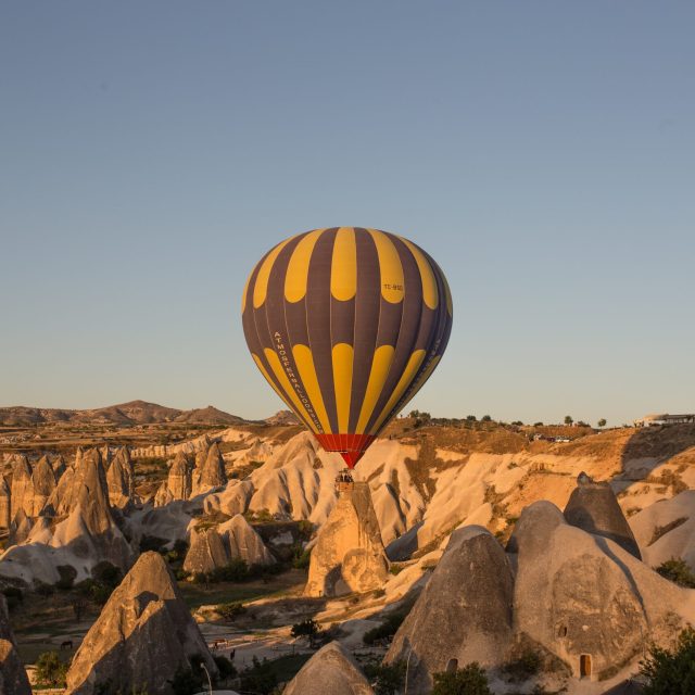 The hot air balloons over the hills and the fields during sunset in Cappadocia, Turkey